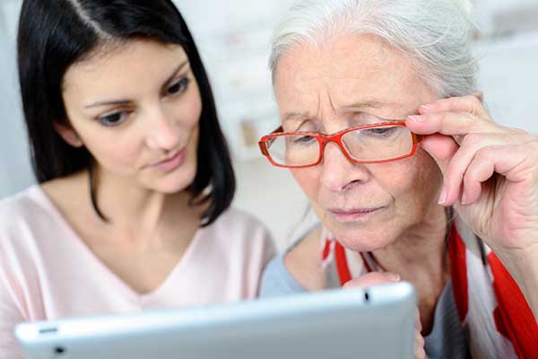 Lady helping elderly woman use computer