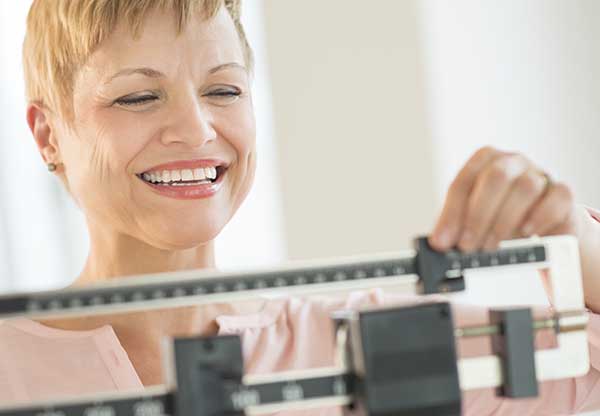 Happy Woman Adjusting Balance Weight Scale
